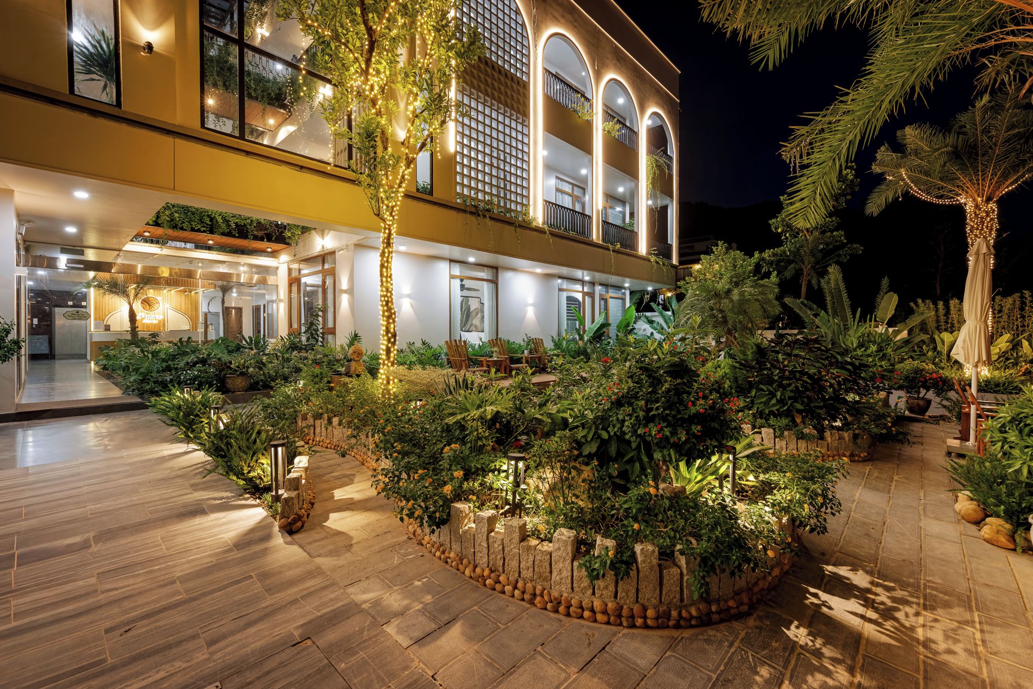 Un hotel con recepción, zona de estar al aire libre y un jardín bien iluminado.