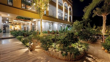 Un hotel con recepción, zona de estar al aire libre y un jardín bien iluminado.