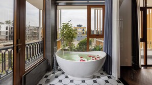 A modern bathroom with a freestanding bathtub, large windows, and a view of the cityscape. - Pataco Tam Coc Hotel (Nam Hoa Lu)