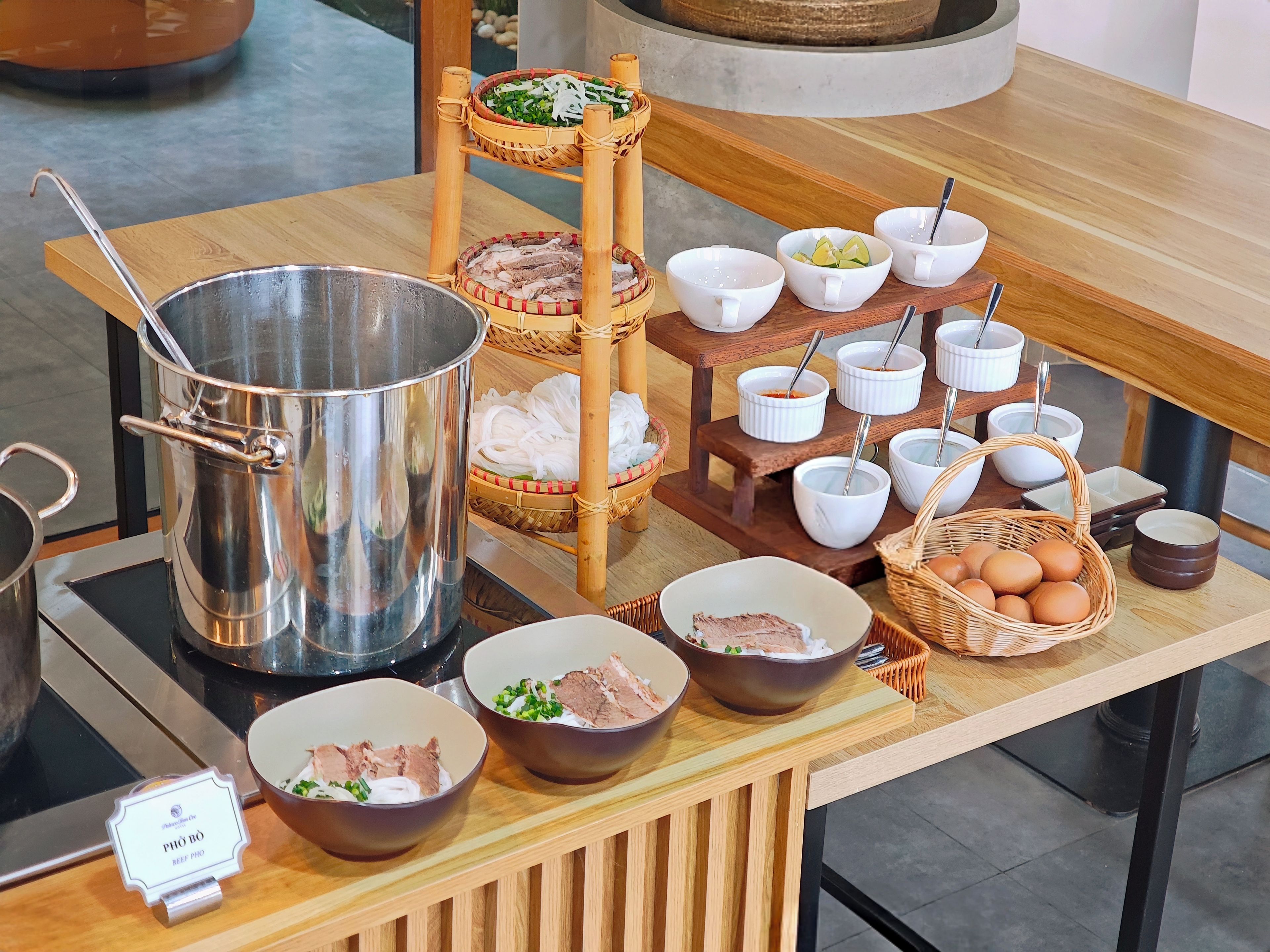 A buffet table with various dishes, including bowls of beef, vegetables, and eggs, and a large metal pot.