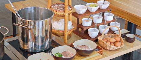 A buffet table with various dishes, including bowls of beef, vegetables, and eggs, and a large metal pot.