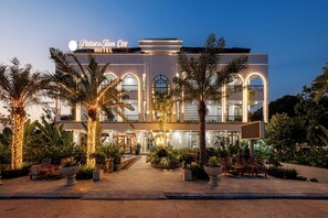 Un hôtel doté d’une façade moderne, de fenêtres en arc de cercle et d’un espace extérieur aménagé pour s’asseoir.