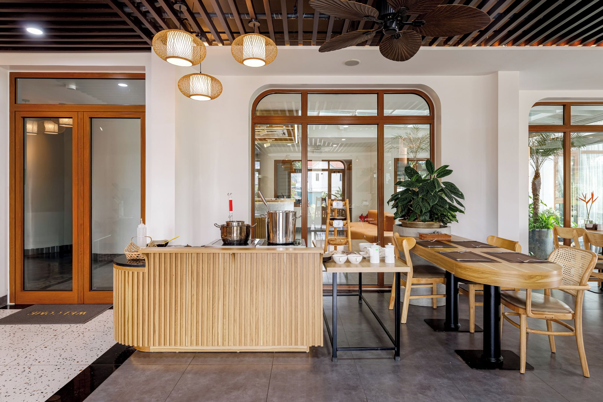 A modern interior with a reception desk, dining area, and large windows.