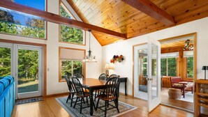 A dining area with a wooden table and chairs, a rug, and a view of the outdoors. - New in 2026! Glidden Pines -Beach Access -July/August Dates Still Avail! (Sturgeon Bay)