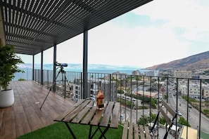 A balcony with a telescope, a bottle, and a potted plant.