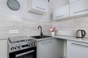 A modern kitchen with a gas stove, sink, and stainless steel kettle. - Spacious Apartment | 3 Bedrooms | Balcony | Arena Katowice (Katowice)
