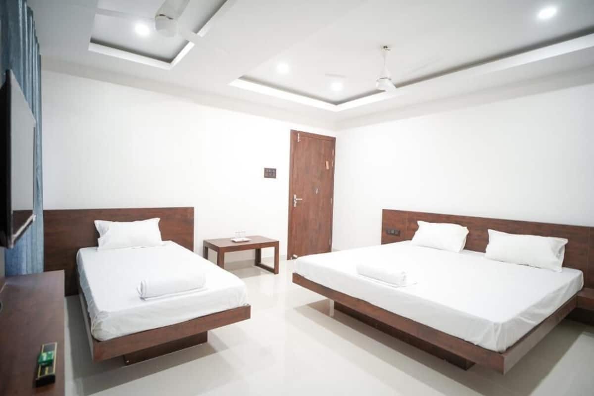 Une chambre d’hôtel moderne avec deux lits, une petite table et un ventilateur de plafond.