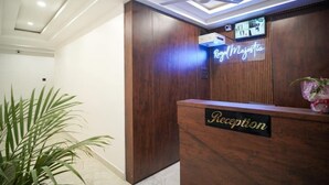 A reception desk with a neon sign reading "Royal Majestic," a ceiling fan, and a potted plant. - Royal Majestic Lodge  (Guwahati)