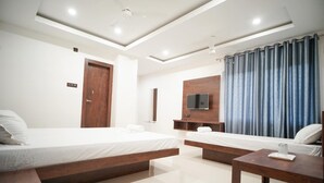 A hotel room with two beds, a TV, a wooden cabinet, and a large window with curtains. - Royal Majestic Lodge  (Guwahati)