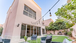 A modern house with a patio area featuring outdoor furniture and a string of lights. - 4BR + Maid’s Room Villa Near Nad Al Sheba Mall, With Easy Access to Major Dubai Attractions (Dubai)