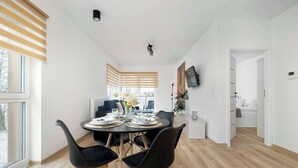 A modern dining area with a round table, black chairs, and a view of a cozy living space.