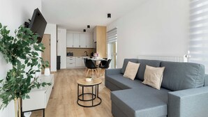 A modern living room with a grey sofa, a round coffee table, and a dining area with a table and chairs.