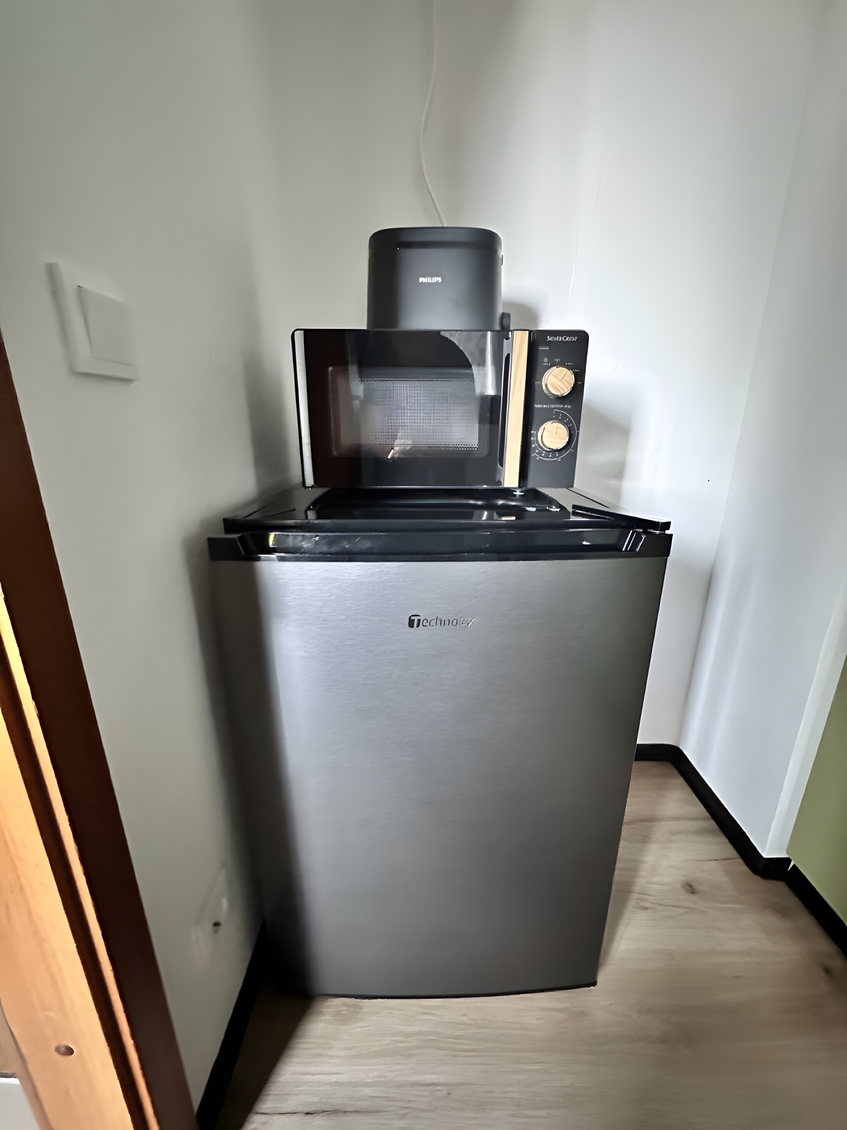 Una cocina compacta con microondas, tostadora y cafetera sobre una estufa empotrada.