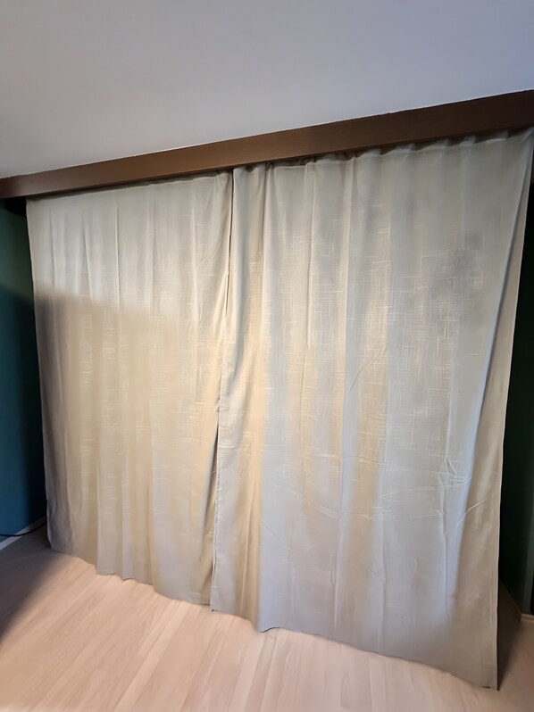 A room with a bed, a wooden headboard, and a sheer curtain.