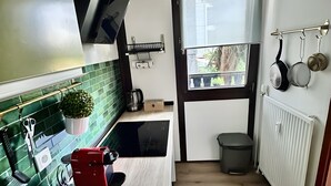 A modern kitchen with a sink, a red appliance, a window, and a radiator.