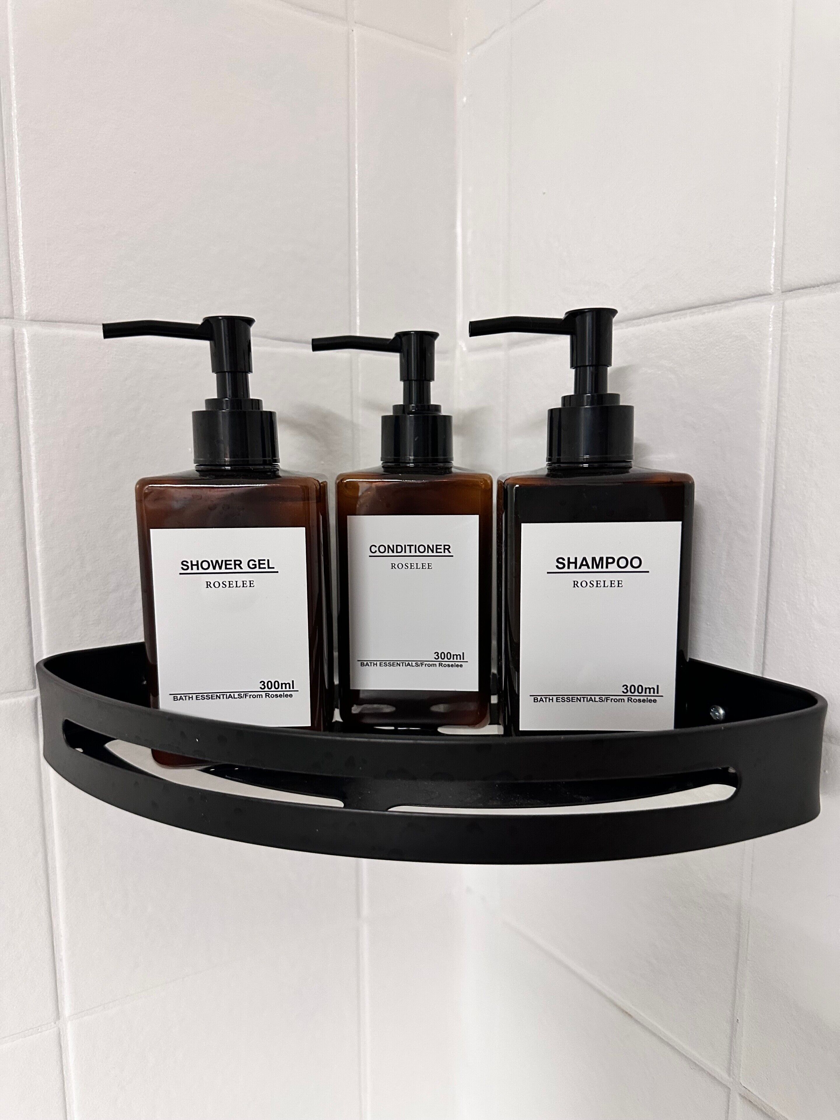 Tres artículos de baño sobre un estante negro frente a una pared de azulejos.