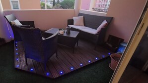 Parvekkeella on rottinkihuonekaluja, pieni pöytä ja ruukussa oleva kasvi.