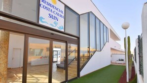 Een modern gebouw met een bord waarop “RESIDENCIAL COSTA CALMA SUN” staat.