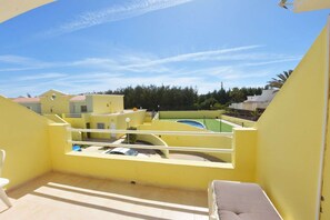 A yellow balcony with a view of a swimming pool and surrounding buildings. - Book Jet - Apartment Tindaya Wifi & Pool (Costa Calma)