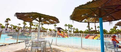 A pool area with umbrellas, chairs, and a fenced swimming pool.