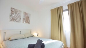 Une chambre d’hôtel comprenant un lit, une table de chevet, une lampe et deux œuvres d’art accrochées au mur.