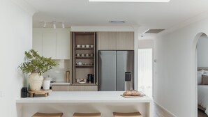Une cuisine moderne avec des meubles blancs, un four encastré et un réfrigérateur en acier inoxydable.