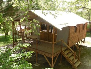 A wooden cabin with a balcony, a staircase, and a small table.