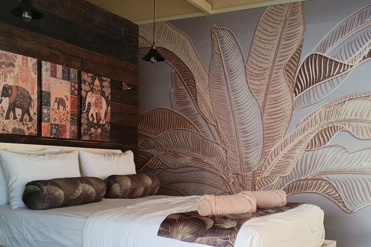 Una camera da letto moderna con un grande letto, un murale e un soffitto in legno.