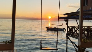 A wooden deck with a swing overlooking a calm sea at sunset. - Turtle Garden Lodge  (Mabul Island)