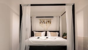 Una cama con dosel y cuatro columnas, ropa de cama blanca y cabecera de madera.