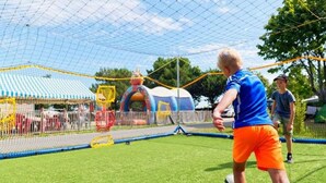 A soccer field with a goal net, a small inflatable structure, and a tent in the background.