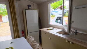 Eine kleine Küche mit Kühlschrank, Spüle und Fenster mit Blick auf ein parkendes Auto.