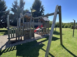 A wooden play structure with a slide and a small shelter. - Cozy mobile home with terrace, 4 people (La Douze)
