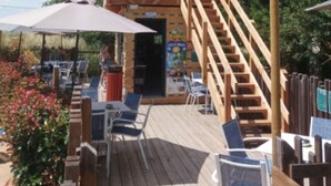 Um deck de madeira com área de estar externa e escada que leva a um andar superior.