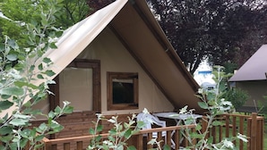 Une petite cabane à toit triangulaire, dotée d’une terrasse en bois et d’une fenêtre.