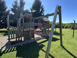 Una estructura de juego de madera con un tobogán y un pequeño refugio.