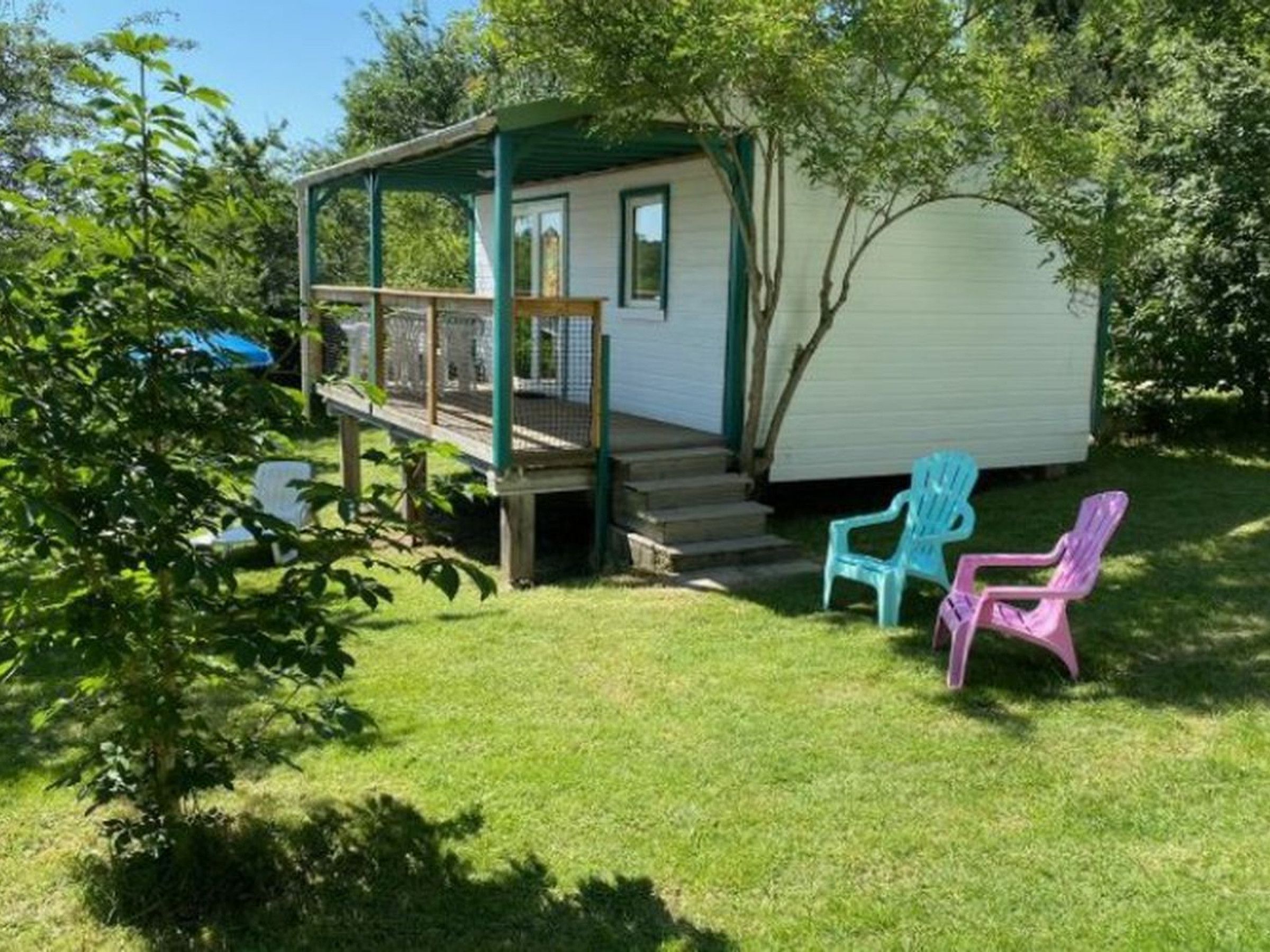 Una casa petita d'una sola planta amb una veranda, un pati tancat i dues cadiretes Adirondack.