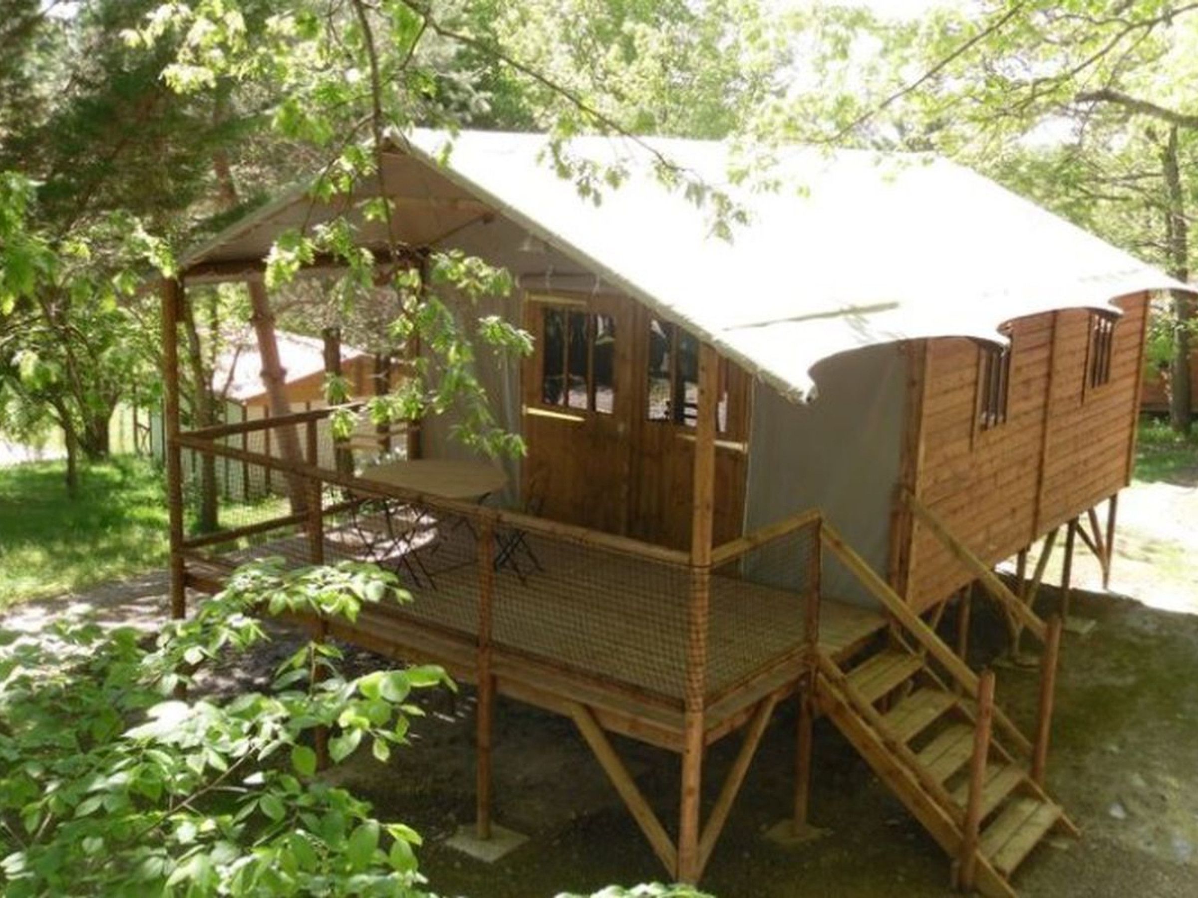 Een houten blokhut met een balkon, een trap en een kleine tafel.