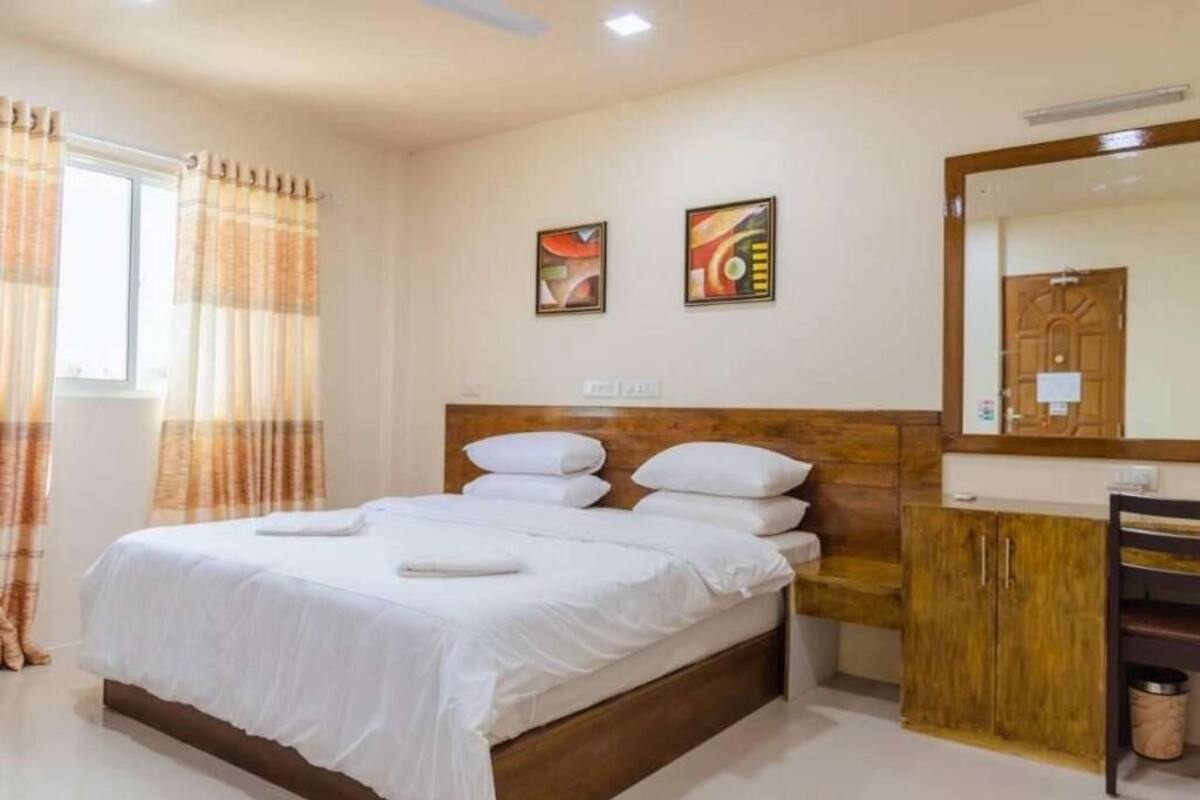 A neatly made bed with white linens, a wooden headboard, and a wooden cabinet with drawers.