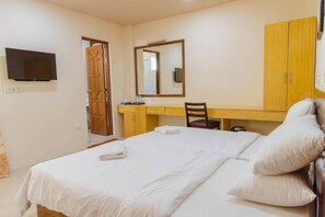 A hotel room with a bed, a desk, a chair, a mirror, and a television. - Oceanvine Maldives (Mahibadhoo)