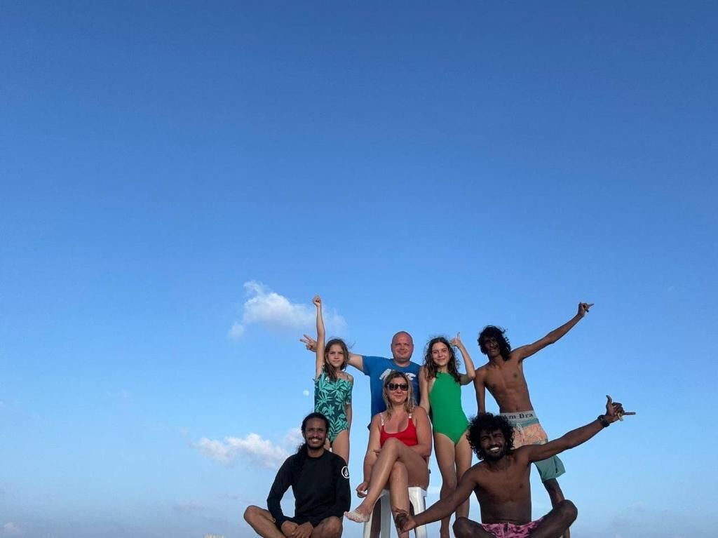 Un grupo de personas posando al aire libre con un cielo azul despejado al fondo.