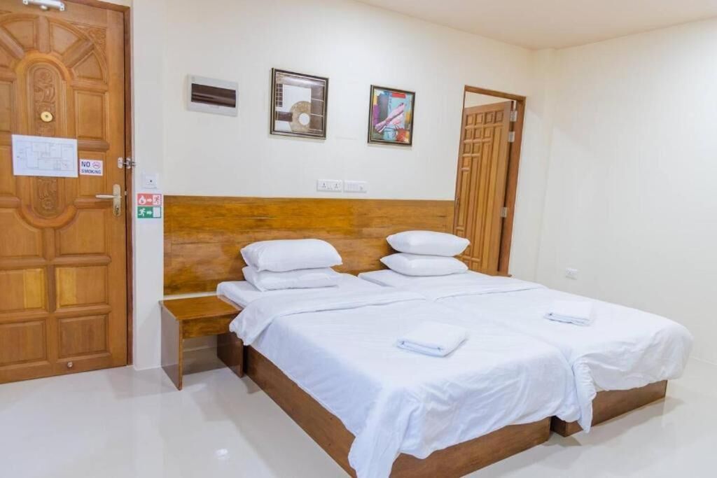 A hotel room with a wooden headboard, a bed with white linens, a bedside table, and a wall-mounted air conditioning unit.