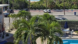 A view of a hotel with a pool, palm trees, and a beach in the background.