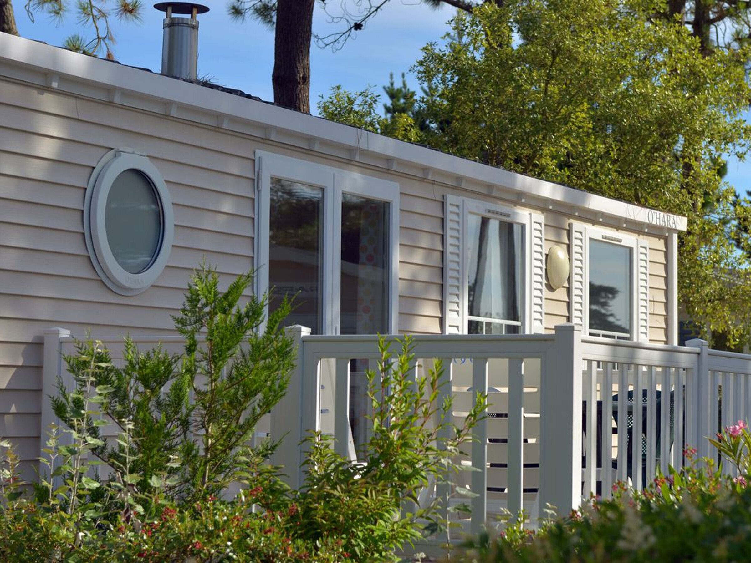 Une maison mobile de plain-pied, avec une façade blanche, une cour avant clôturée et une cheminée.
