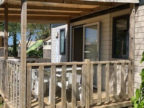 A wooden deck with a railing, a covered area with a door, and a small table with chairs. - Comfortable mobile home with terrace in Tréguennec (Tréguennec)