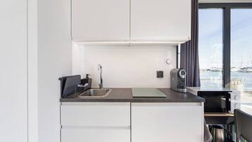 A modern kitchen with a stainless steel sink, a kettle, and a coffee maker.