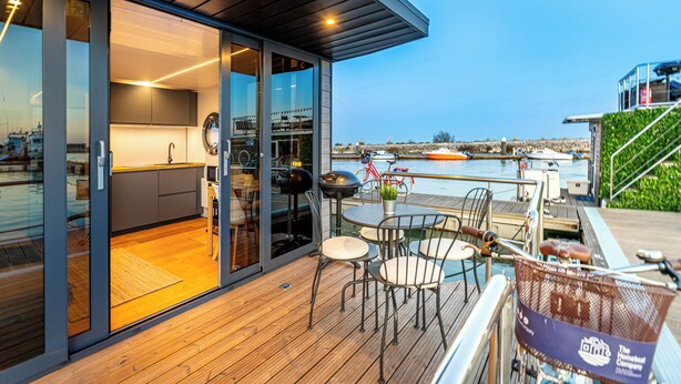Una terraza moderna al aire libre con zona de comedor, una parrilla y vista al agua.