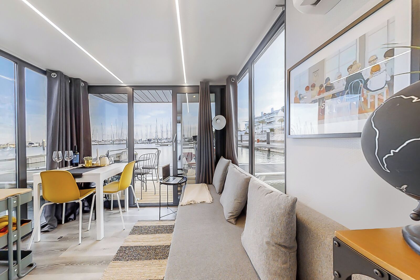 A modern hotel room with a balcony, a dining area, and a sofa.