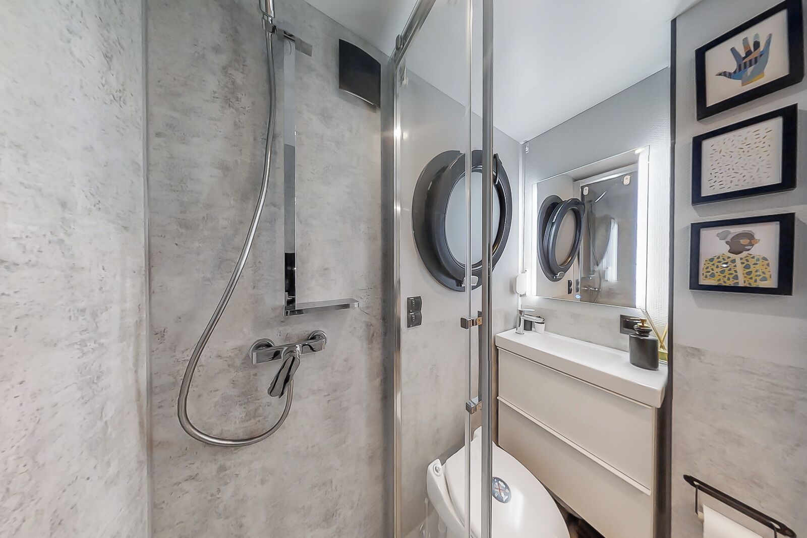 A modern bathroom with a glass-enclosed shower, a round mirror, and a toilet.