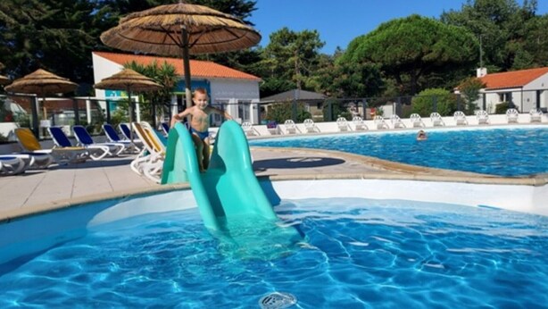 A swimming pool with a slide, lounge chairs, and umbrellas. - Spacious mobile home, terrace, 3 bedrooms in Saint-Hilaire-de-Riez (Saint-Hilaire-de-Riez)